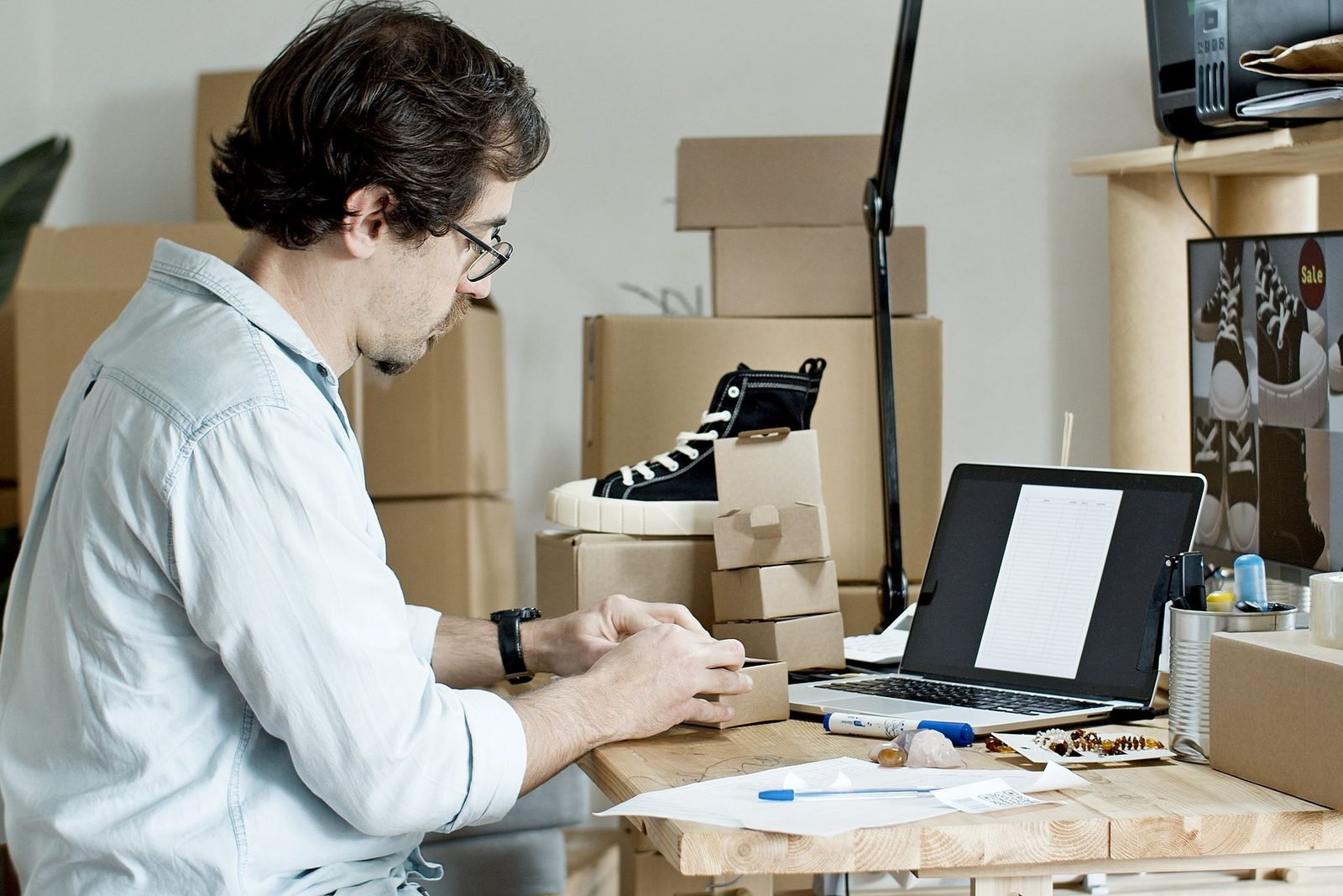 Lojista embalando produtos e acompanhando os pedidos da loja online no notebook