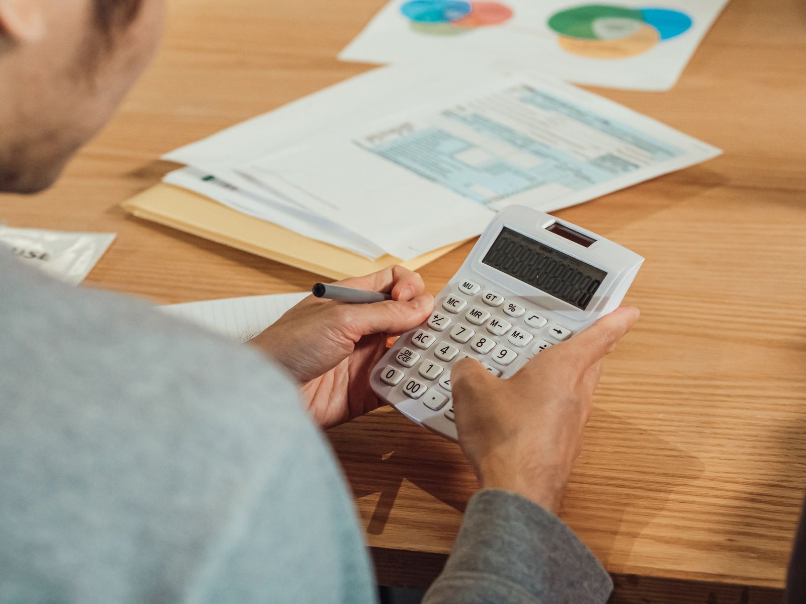 Mãos usando a calculadora sobre relatórios financeiros na mesa do escritório