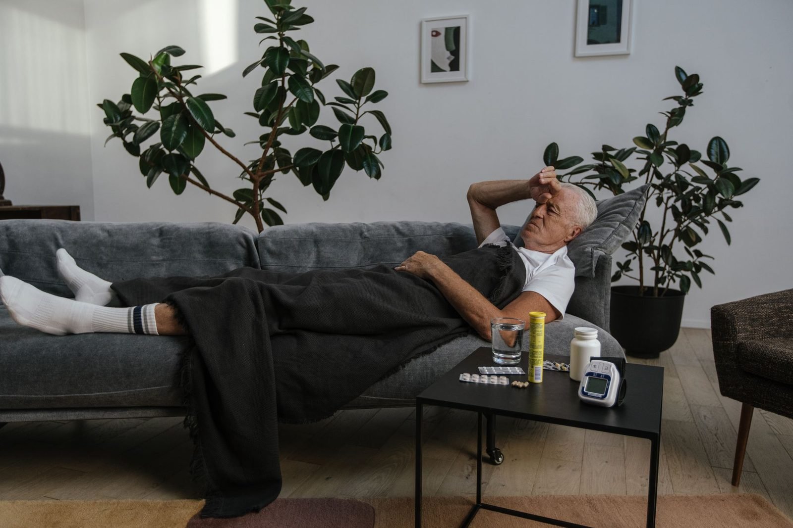 Homem descansando no sofá, com remédios na mesa ao lado