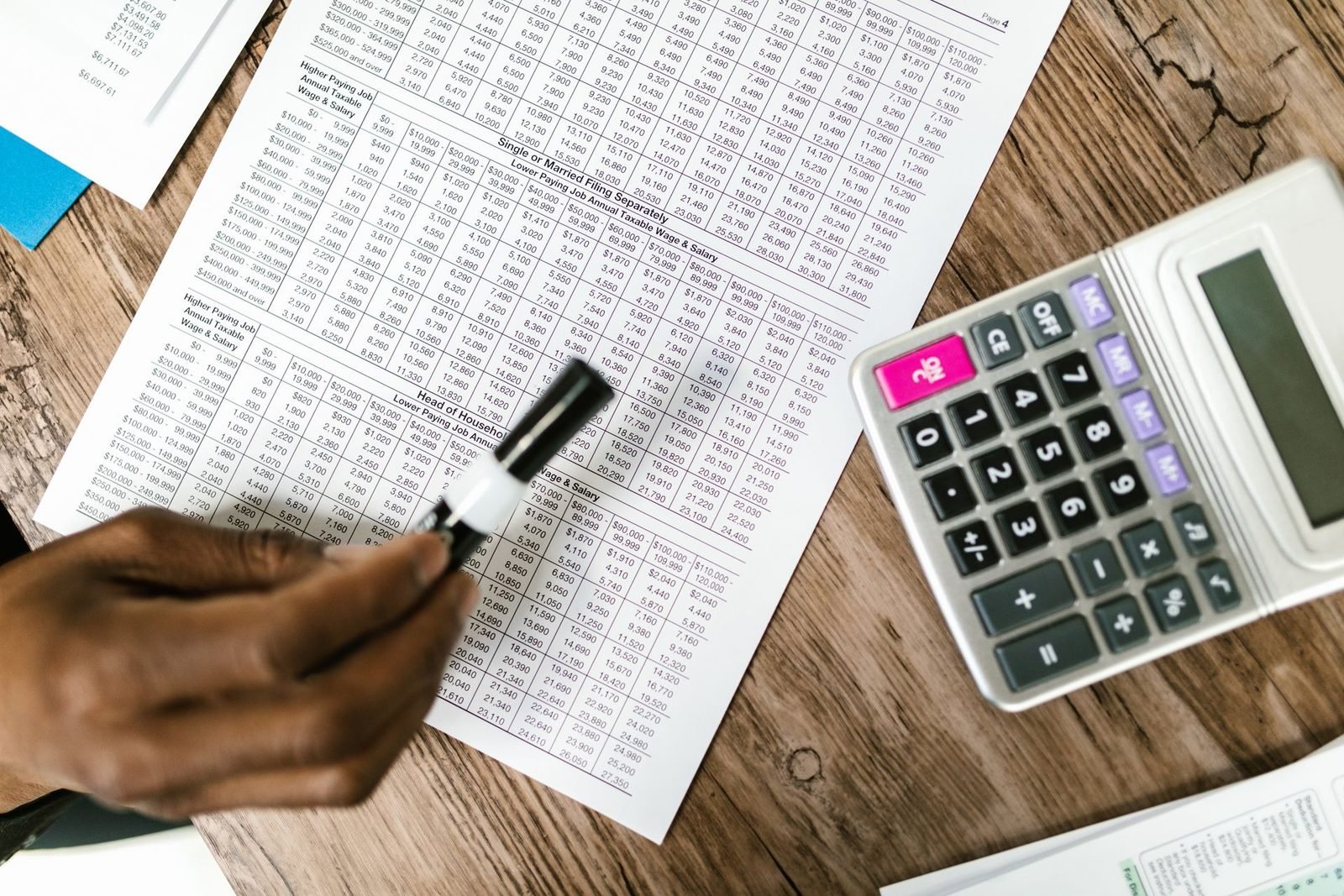 Guias e documentos de imposto ao lado de uma calculadora sobre a mesa de madeira