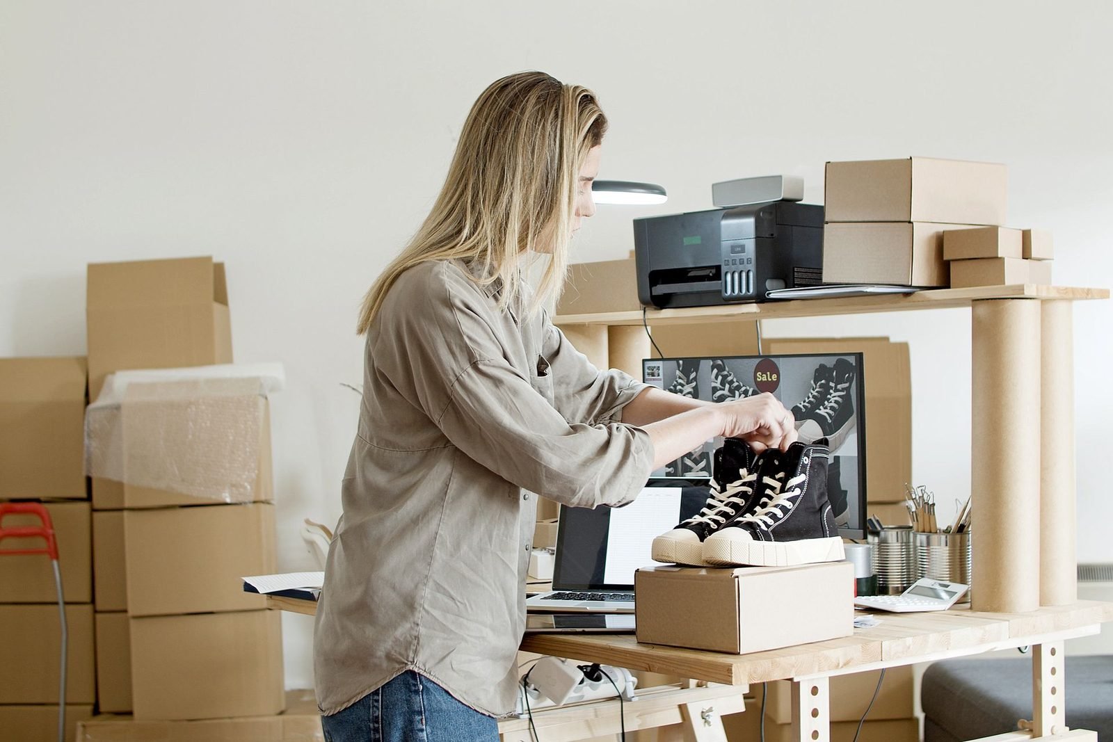 Vendedora embalando um par de tênis em uma caixa no seu espaço de e-commerce