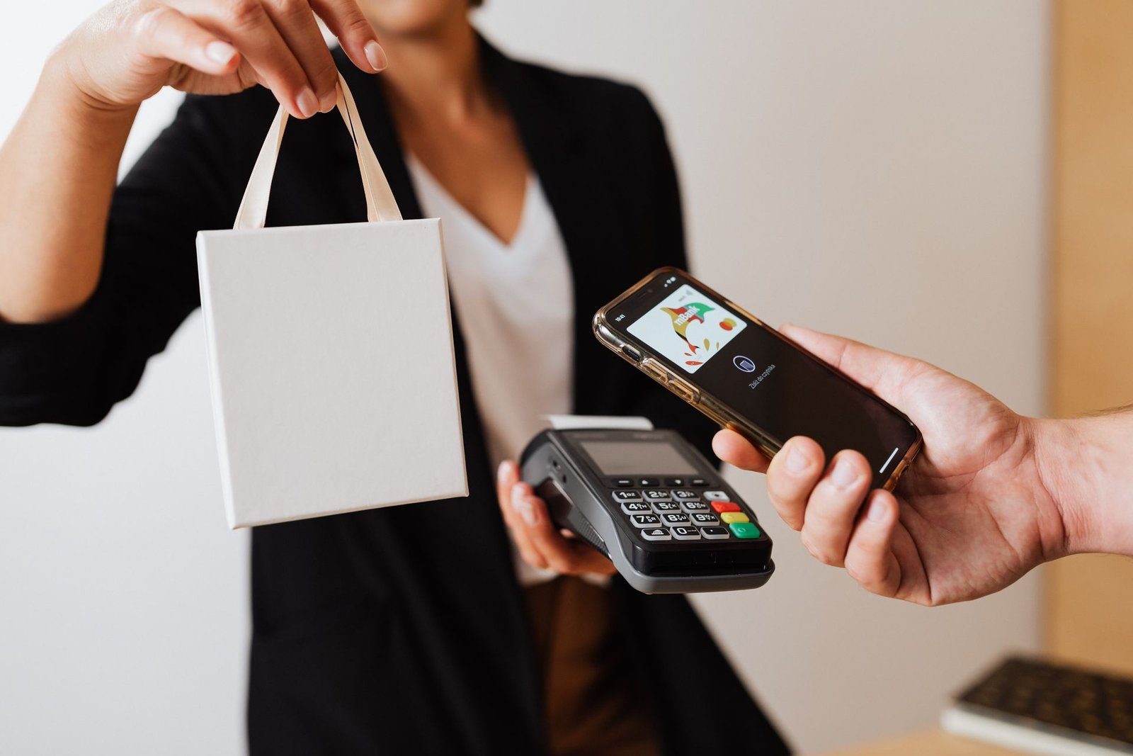 Cliente pagando por aproximação com o celular e recebendo a sacola da compra