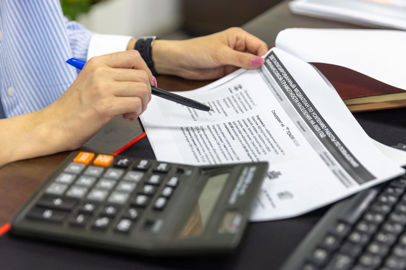 Mãos conferindo documentos financeiros com calculadora e caneta