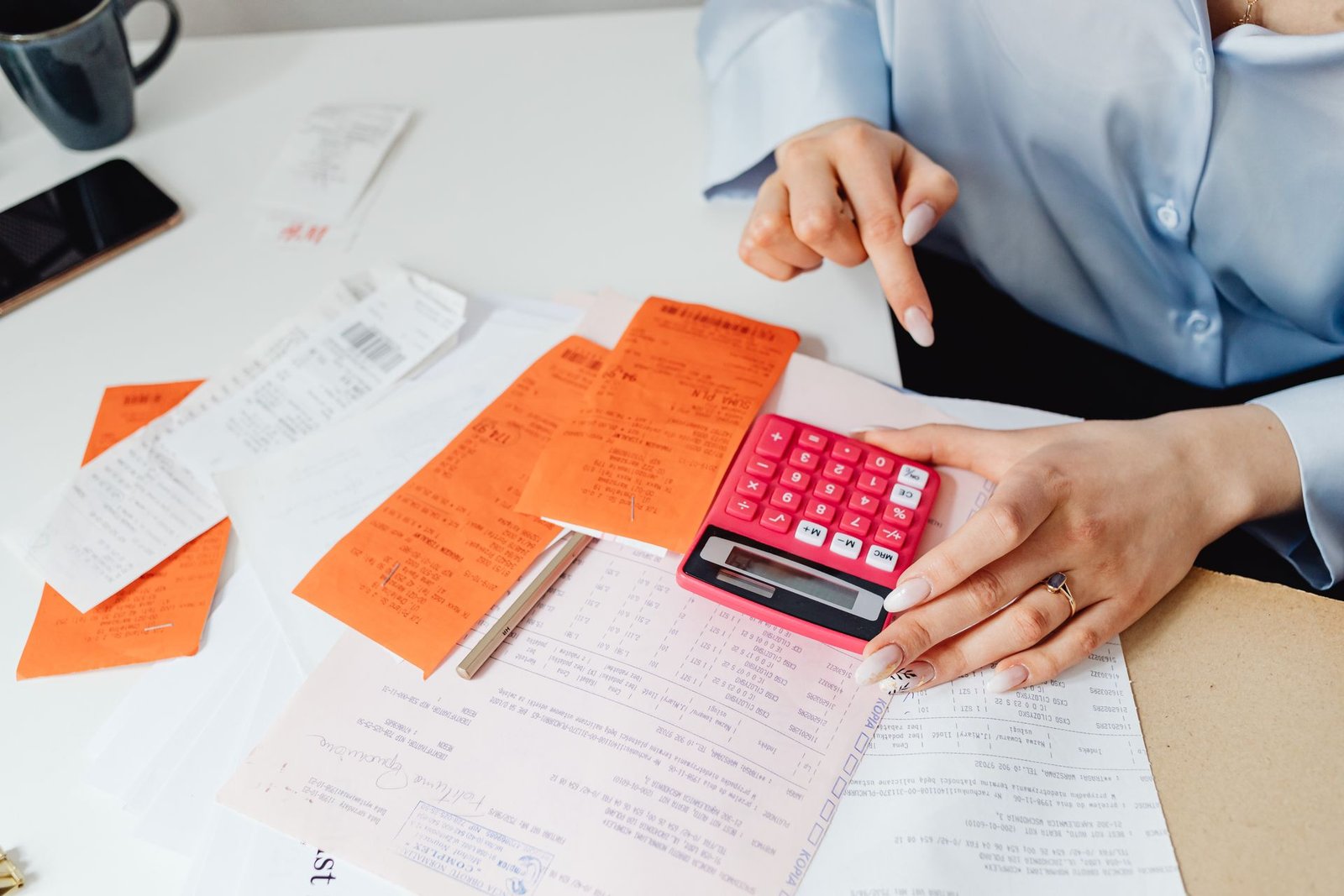 Empresária calculando a folha de pagamento com recibos e calculadora na mesa