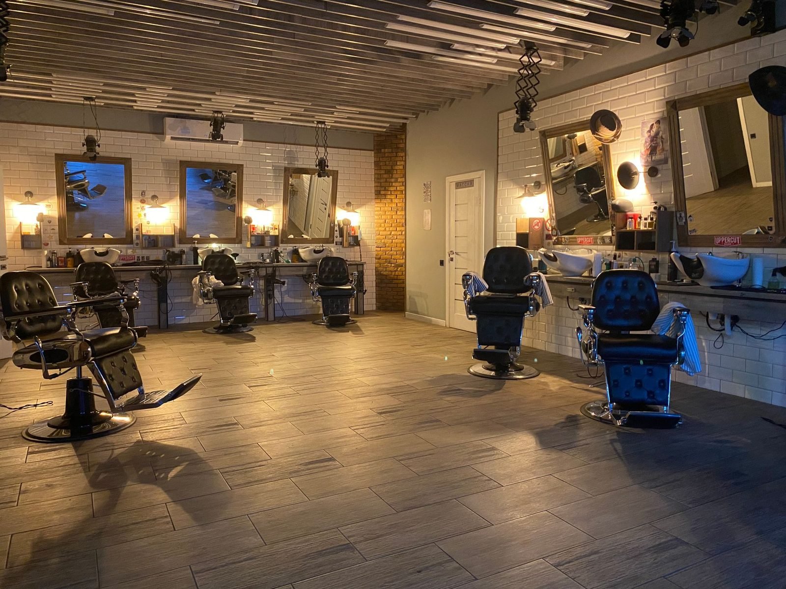 Barbearia vazia, com cadeiras enfileiradas e espelhos iluminados