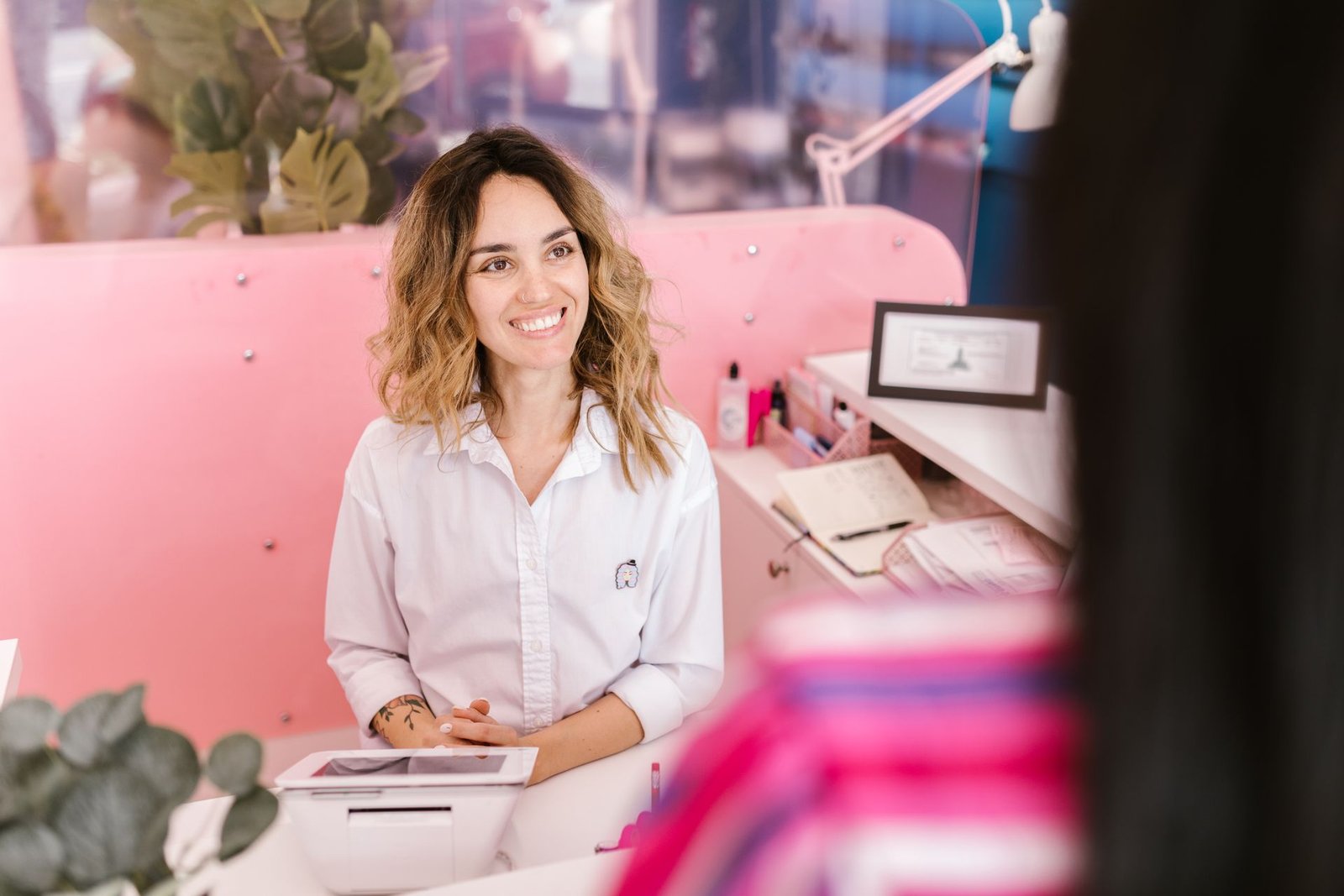 Recepcionista sorrindo atrás do balcão de um salão de beleza