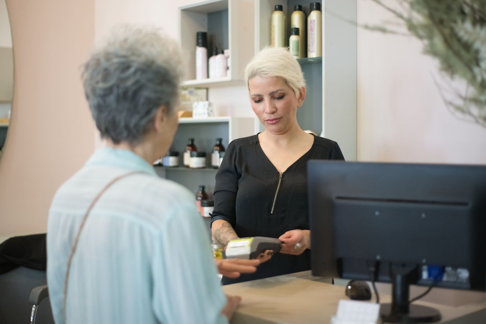 Cliente pagando na maquininha de cartão no balcão de um salão de beleza